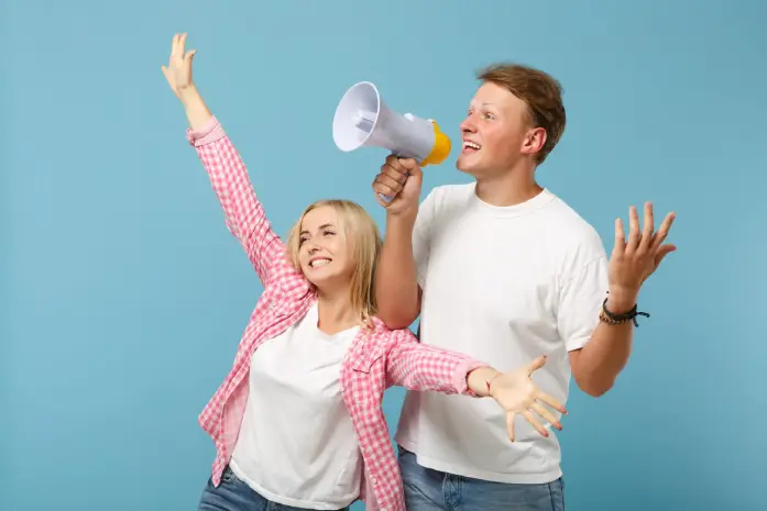 A cheerful young woman and man posing, with the man holding a megaphone.